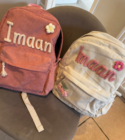 Two corduroy backpacks embroidered 'Imaan' in pink and cream